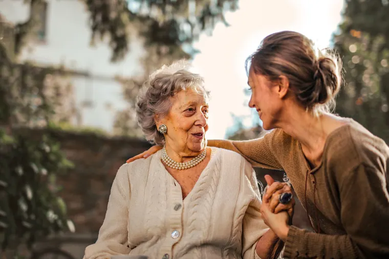 Filha conversando e sorrindo com a mãe idosa